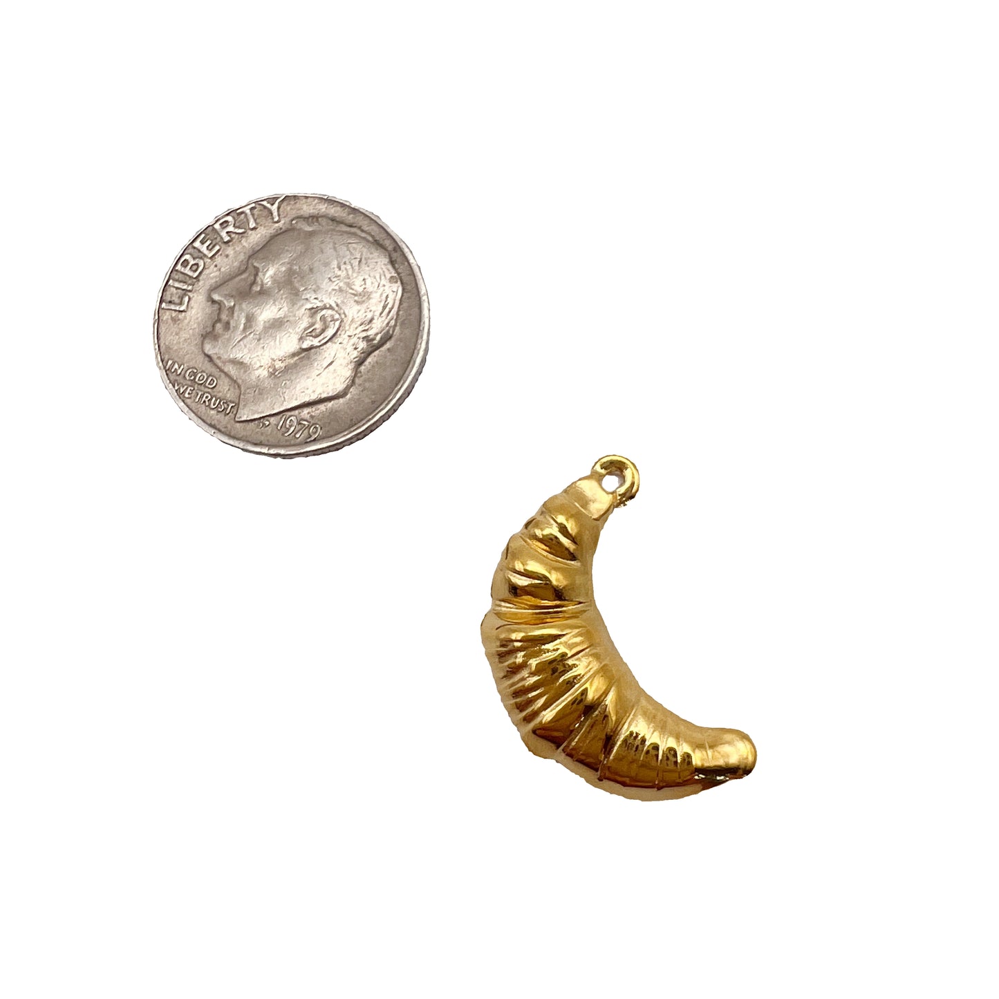 Gold crescent moon charm next to a quarter on a white background