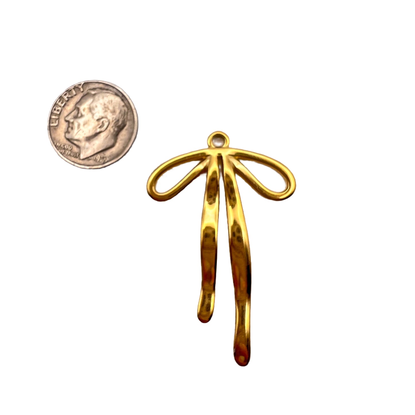 Gold pendant next to a penny on a light gray background