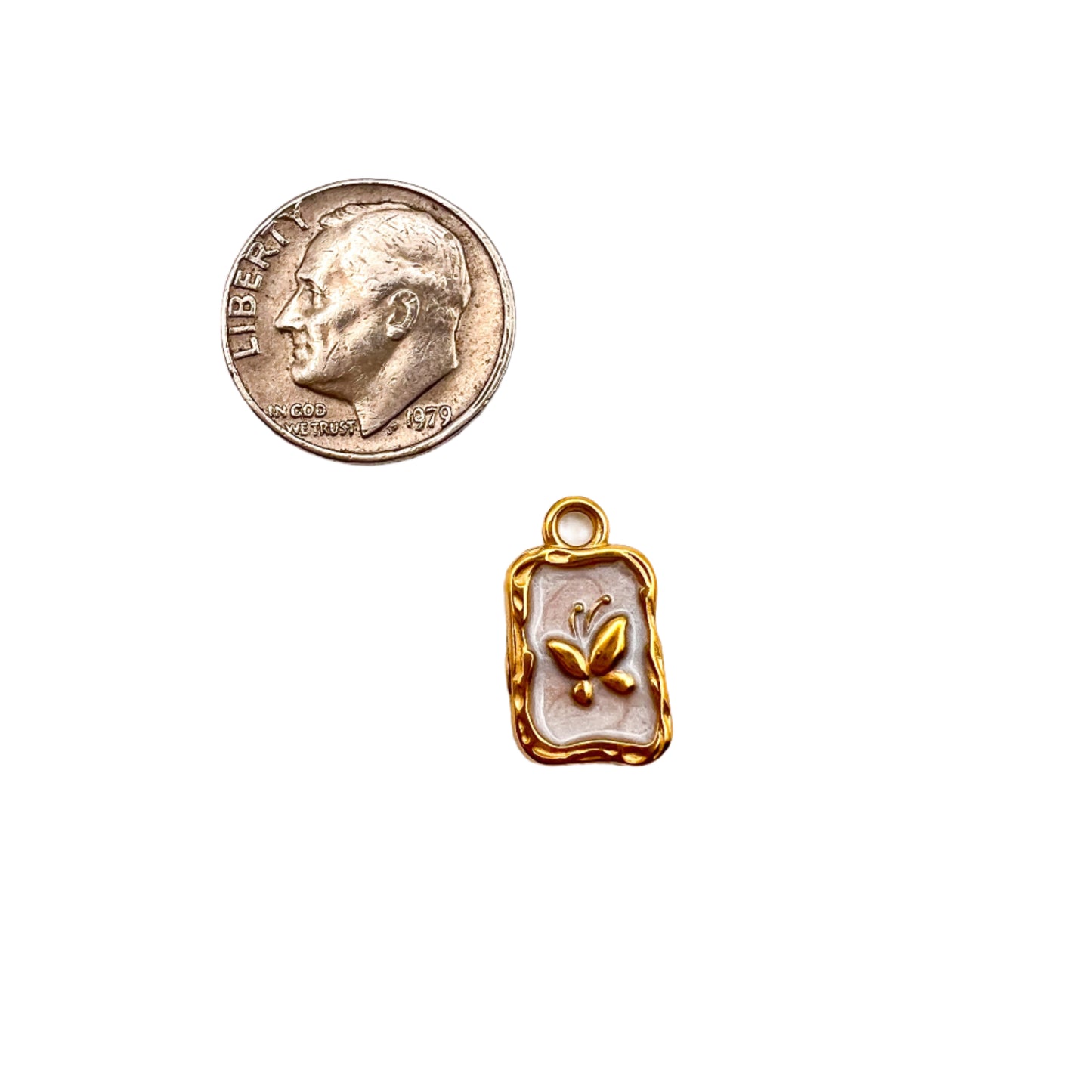 Small gold pendant with a butterfly design next to a U.S. quarter on a white background