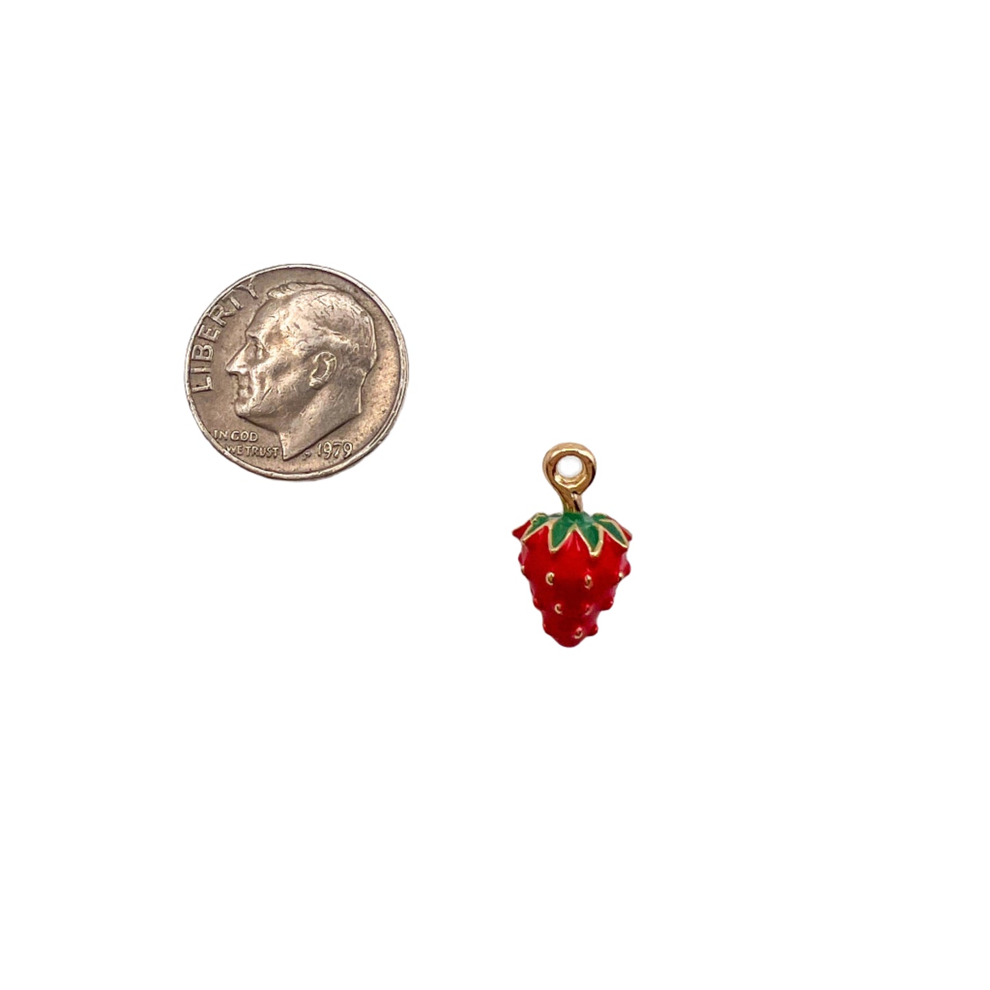 Red strawberry charm next to a dime on a white background