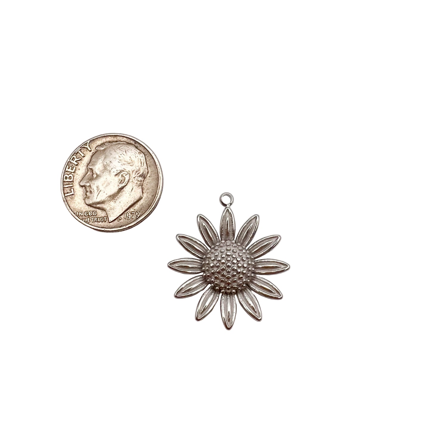 Silver flower-shaped pendant next to a U.S. quarter for size comparison on a white background