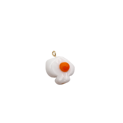 Pendant shaped like a fried egg on a white background