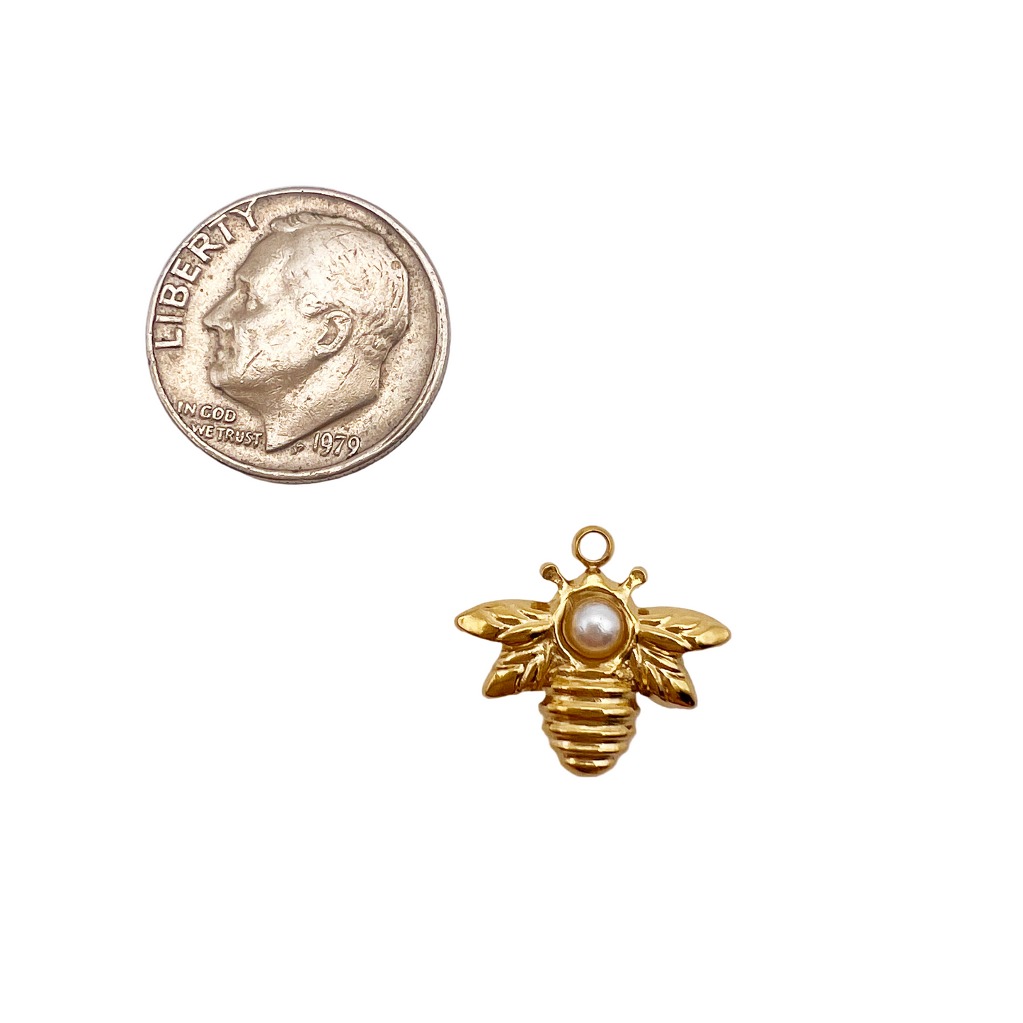 Gold bee charm with pearl on a white background next to a quarter
