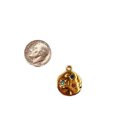 Gold pendant with colorful stones next to a quarter on a white background