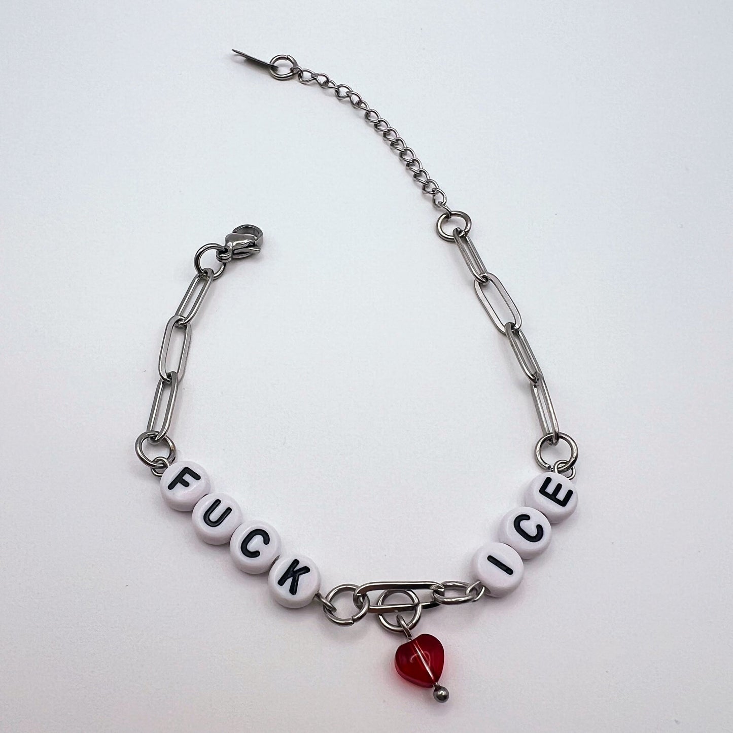 Bracelet with letter beads and a red heart charm on a white background
