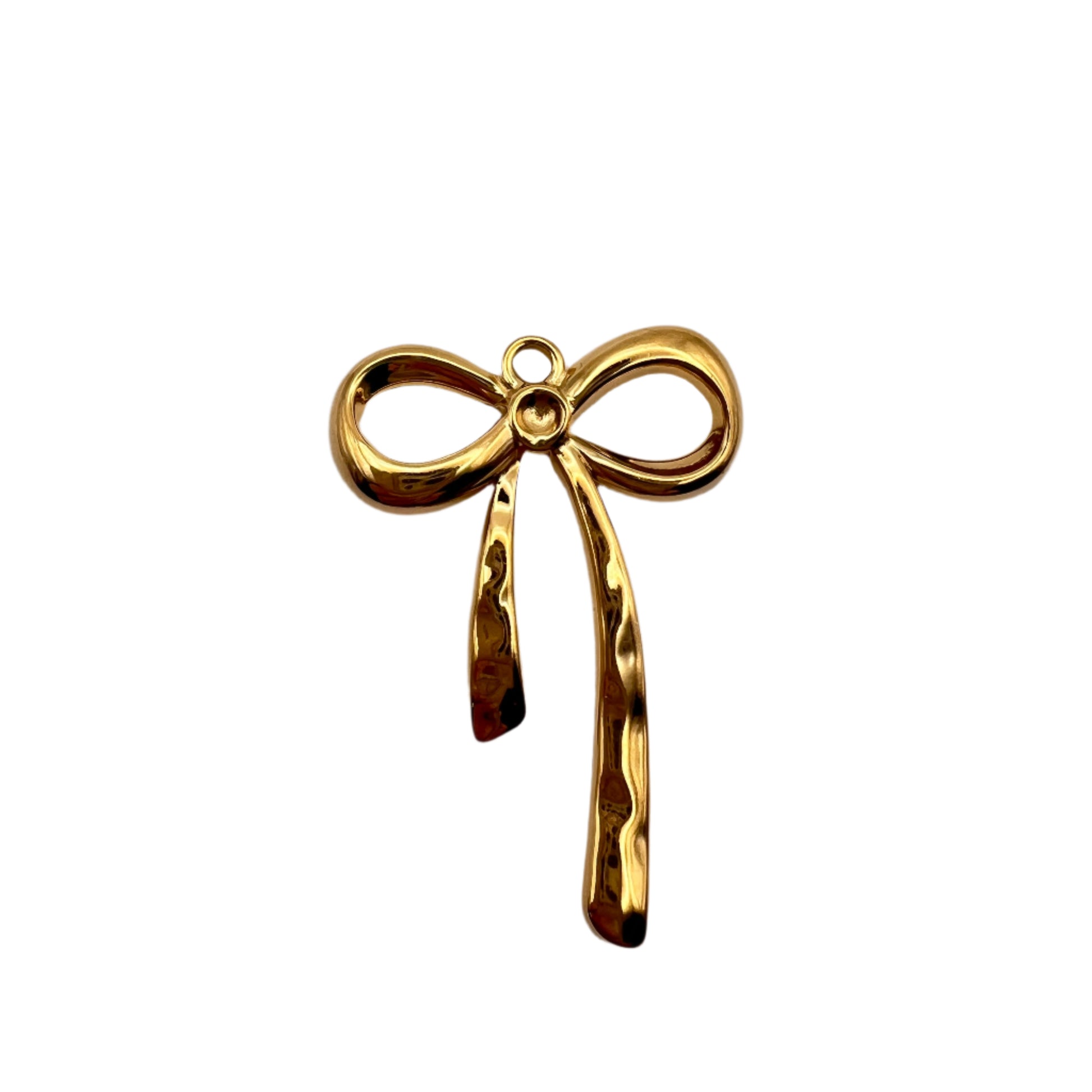 Gold bow-shaped jewelry piece on a light gray background