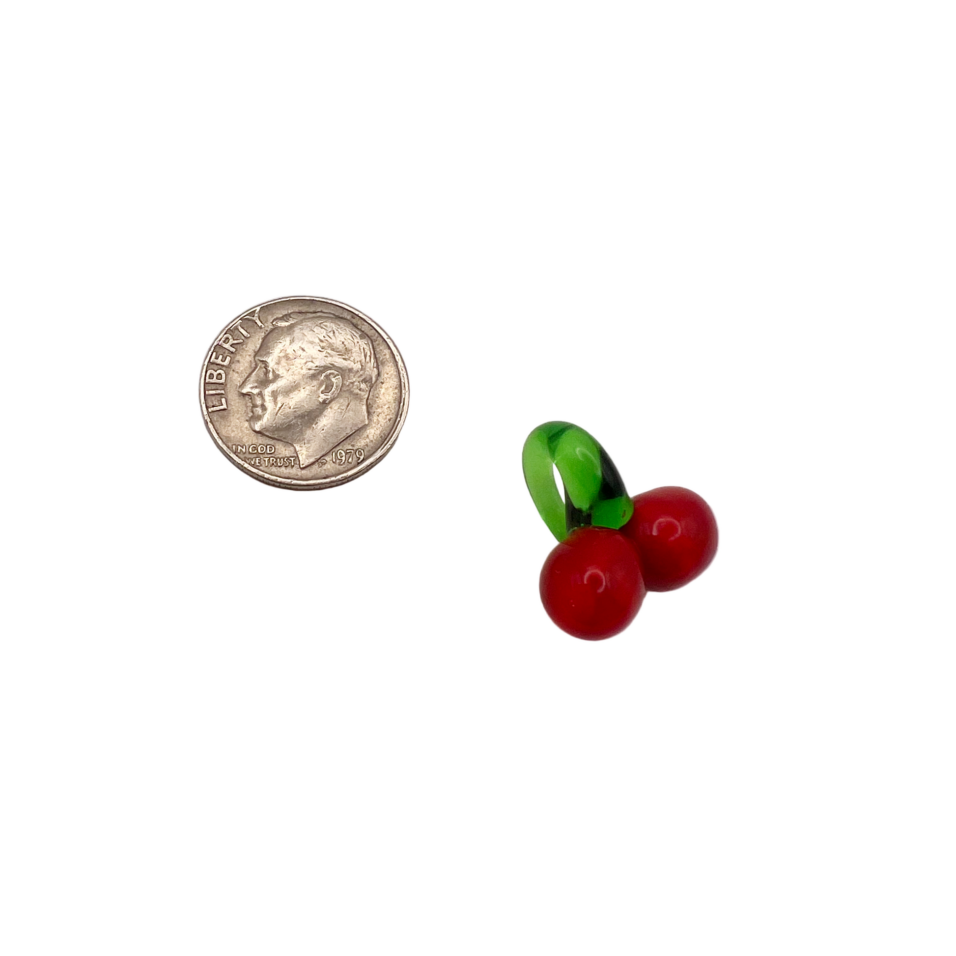 Two small glass cherries next to a quarter on a white background