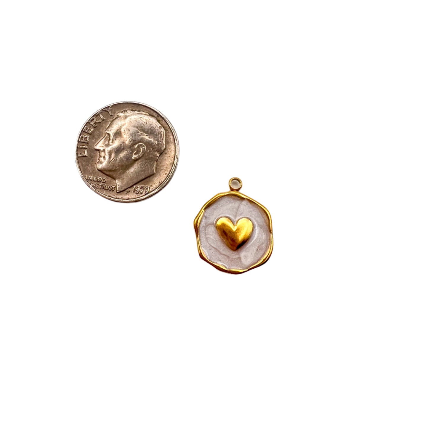 Small gold pendant with a heart design next to a penny on a white background