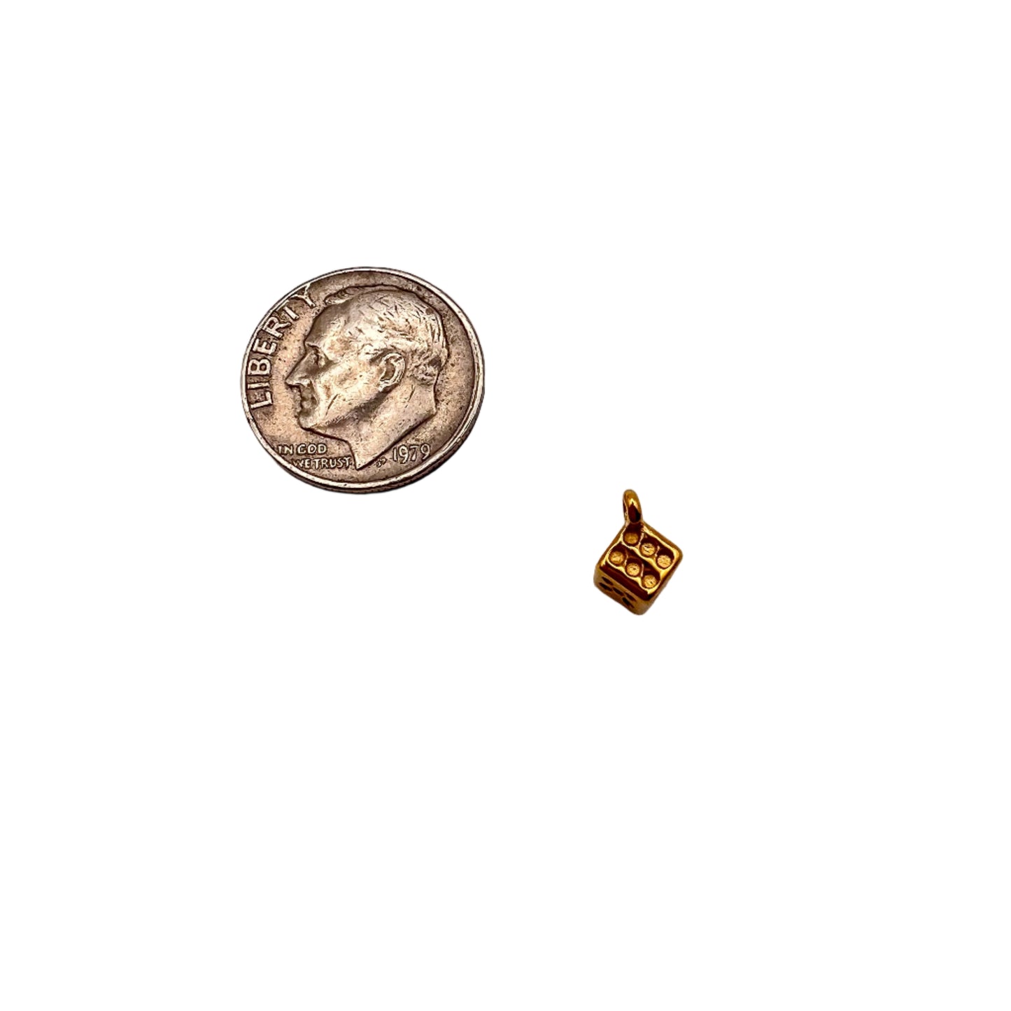 Small gold cube charm next to a U.S. quarter on a white background
