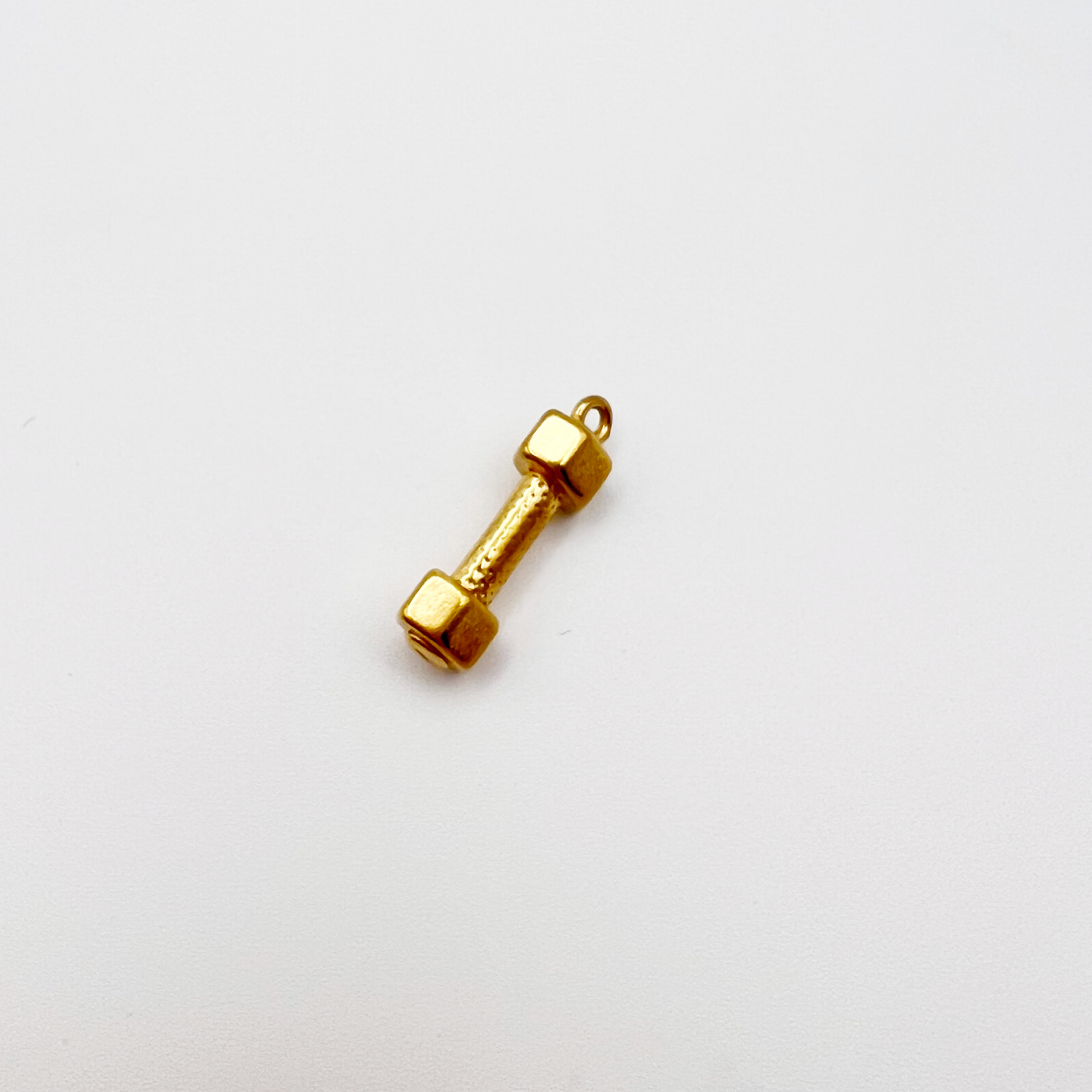 Gold dumbbell-shaped charm on a white background