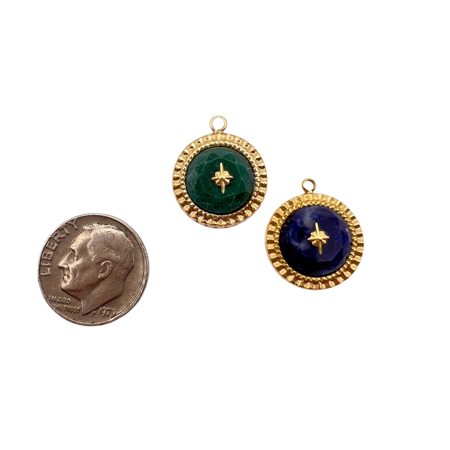 Two round gold-framed green and blue stones with a penny for scale on a white background