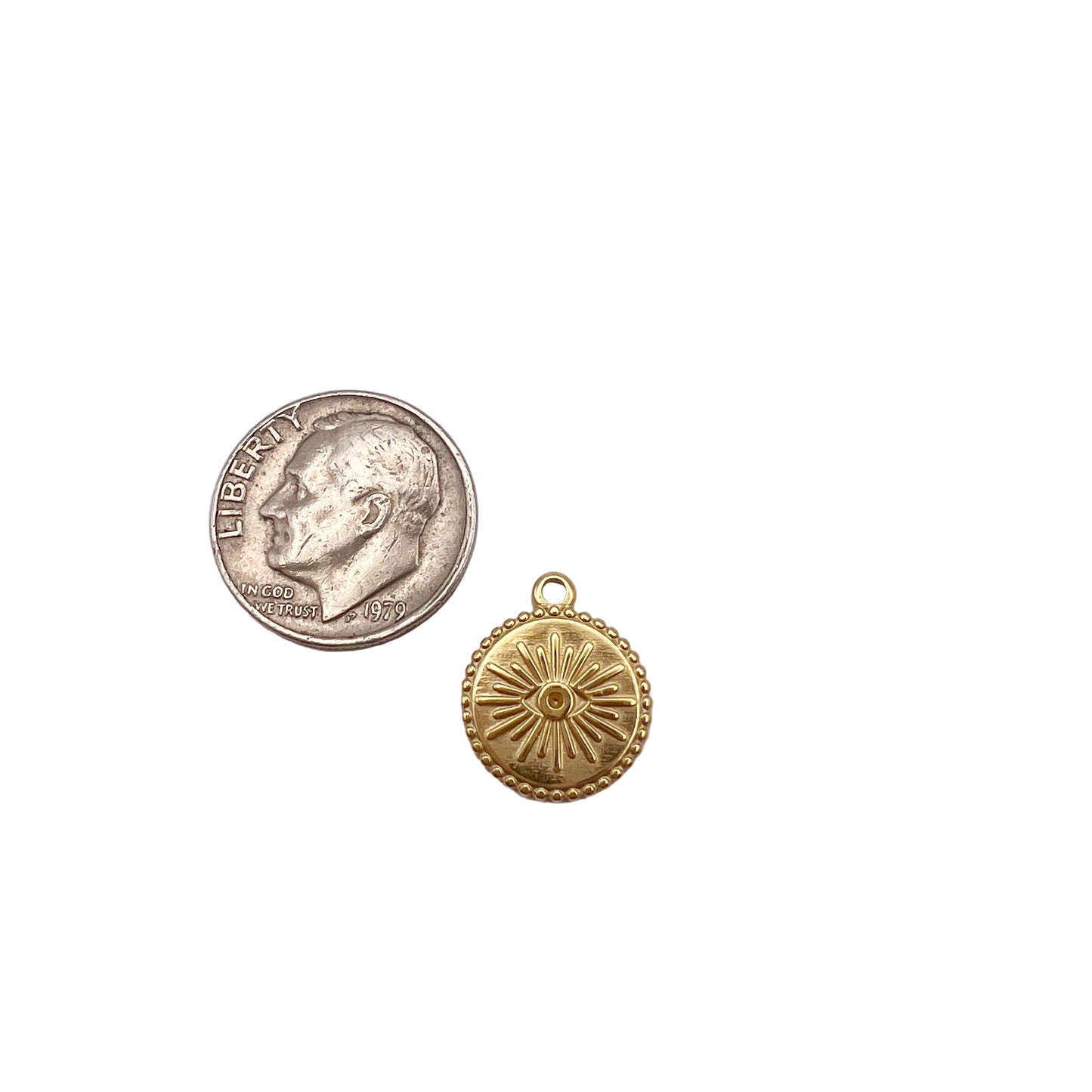 Gold pendant next to a silver dollar coin on a light gray background