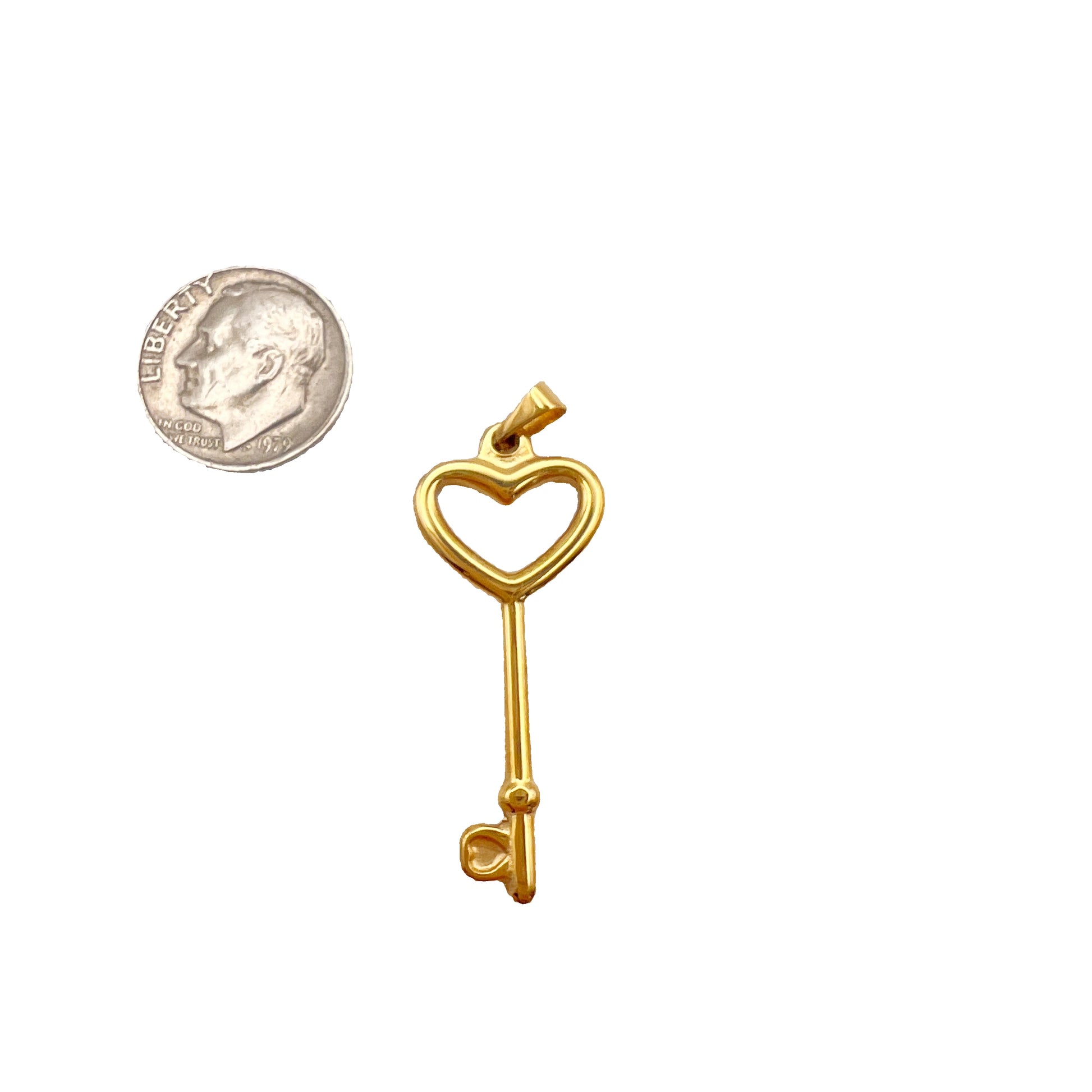 Gold key-shaped pendant with heart design next to a quarter for scale on a white background