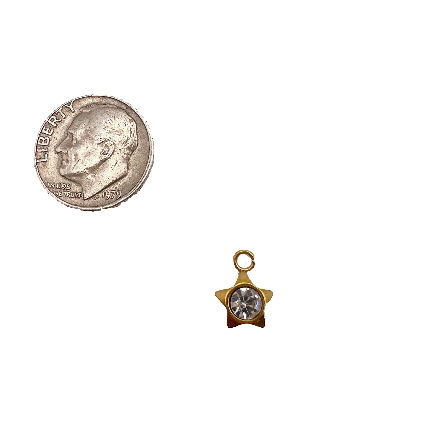 Gold star-shaped charm with a clear gemstone next to a quarter on a white background