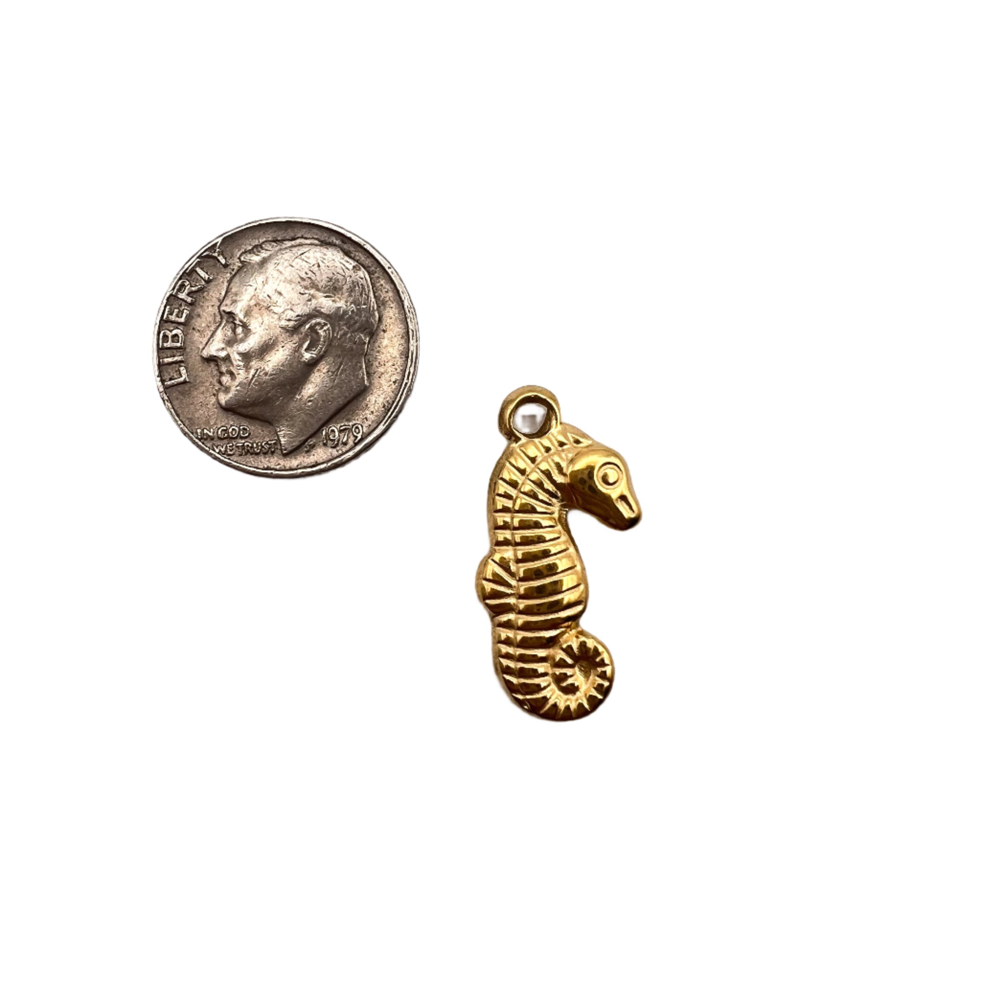 Gold seahorse charm next to a quarter on a white background