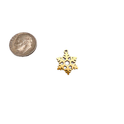 Gold snowflake charm next to a quarter on a light gray background