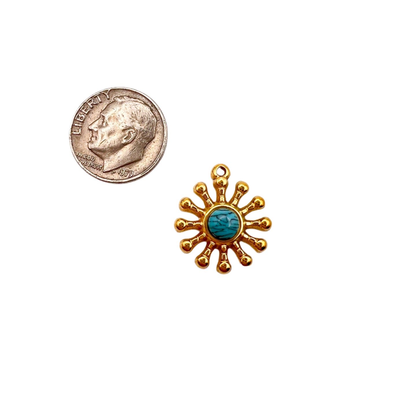 Gold sun-shaped pendant with turquoise center next to a penny on a white background