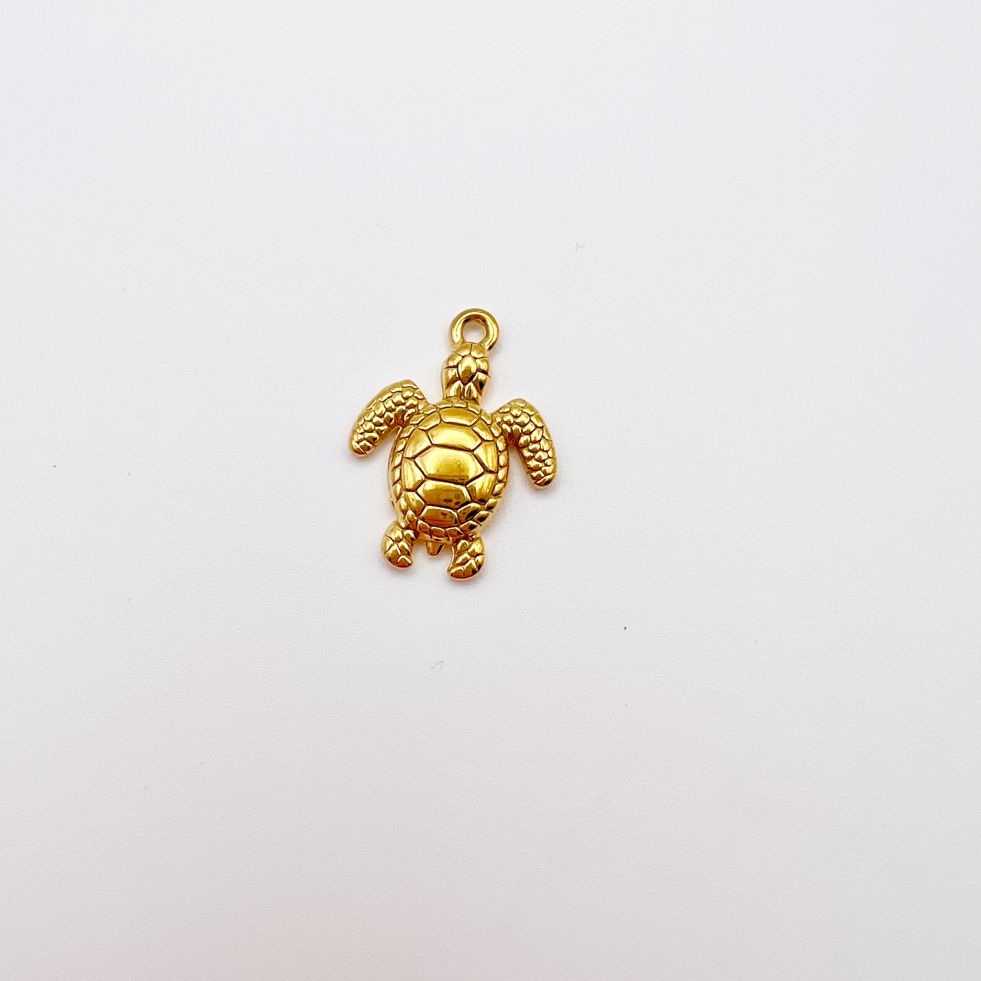 Gold turtle charm on a light gray background