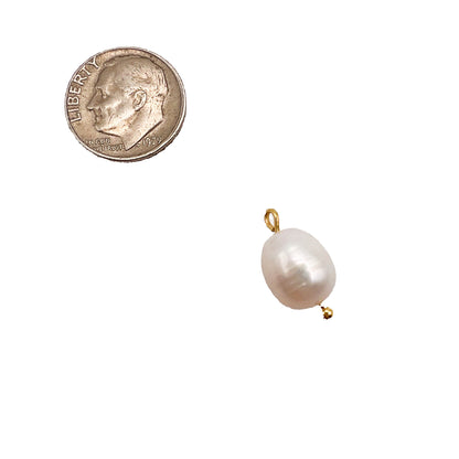 Pearl pendant next to a quarter on a white background