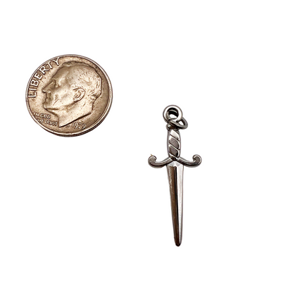 Silver dagger-shaped pendant next to a coin on a white background