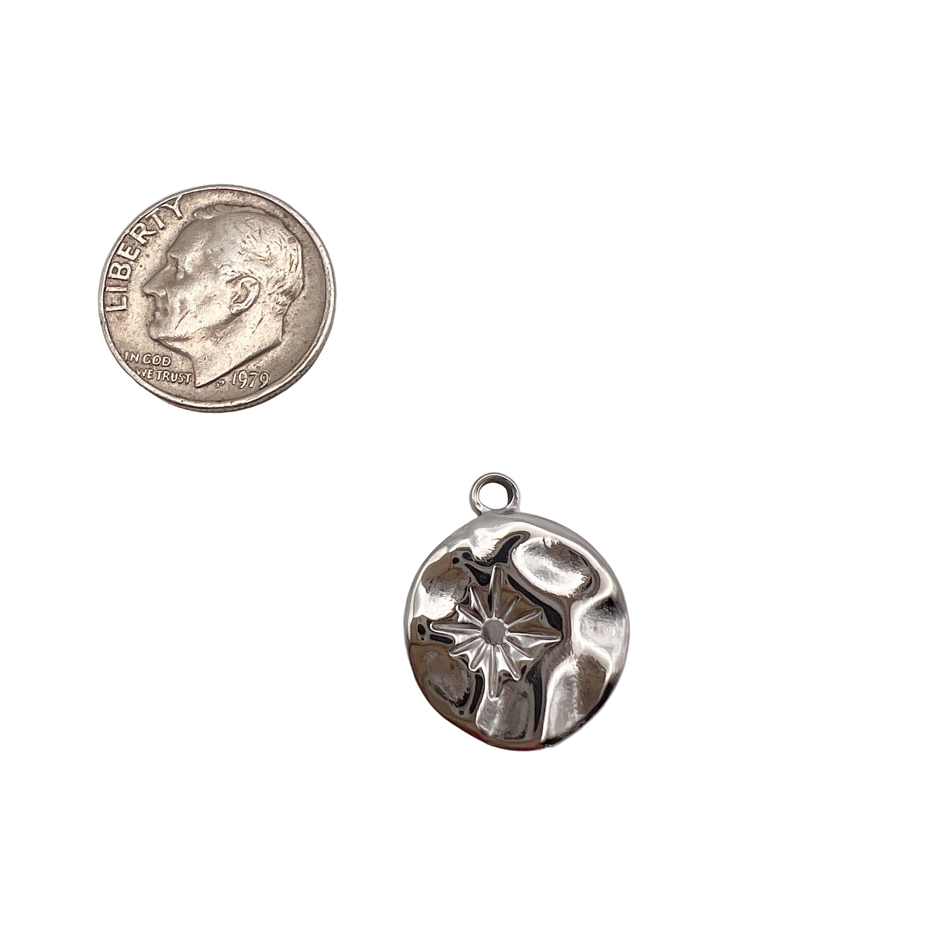 Silver pendant next to a quarter on a white background