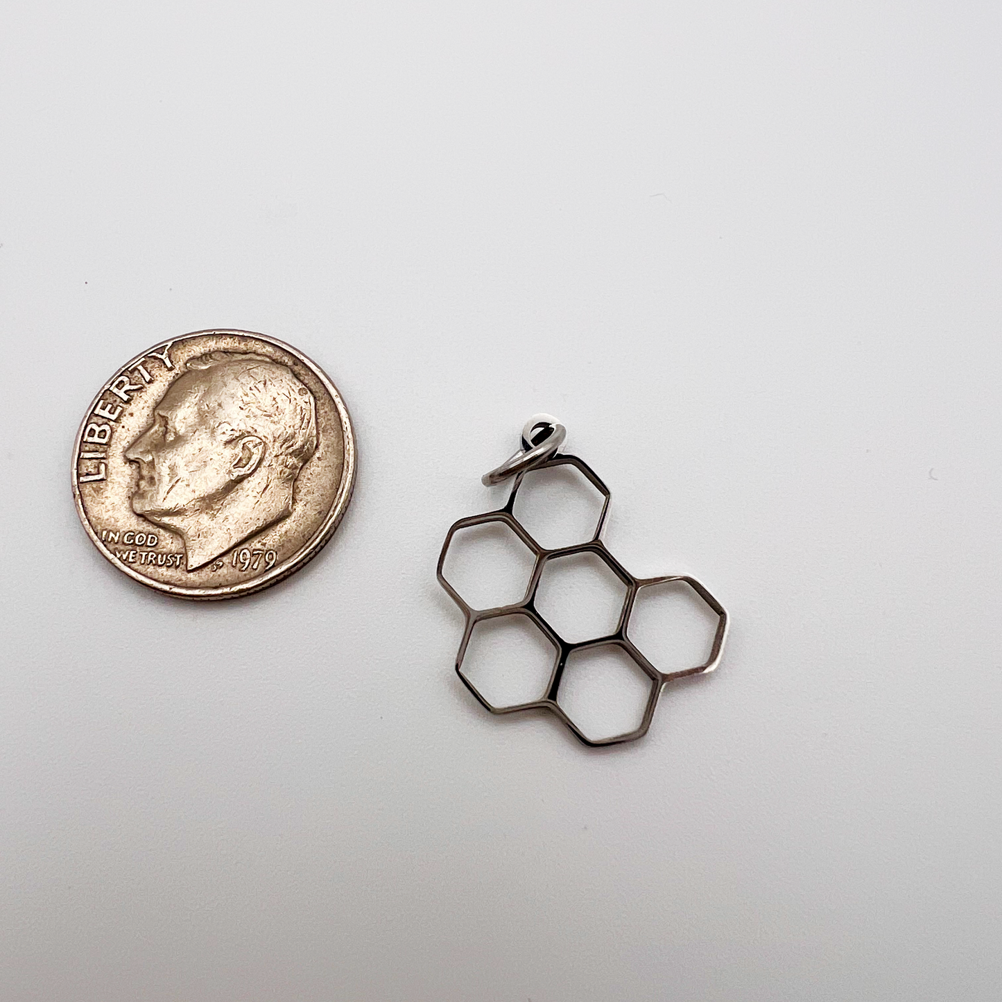 Metallic honeycomb-shaped object next to a coin on a white background