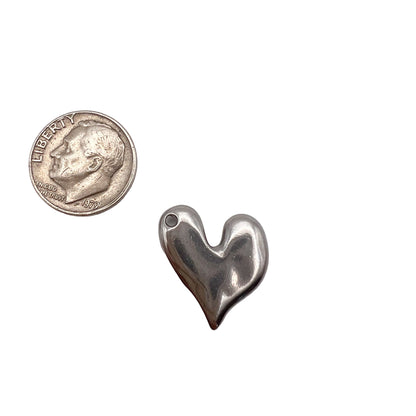 Silver heart-shaped pendant next to a quarter on a white background