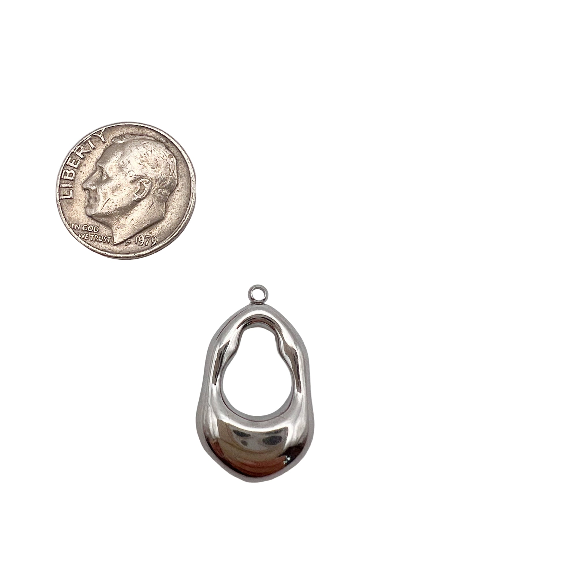 Silver pendant next to a quarter on a light gray background