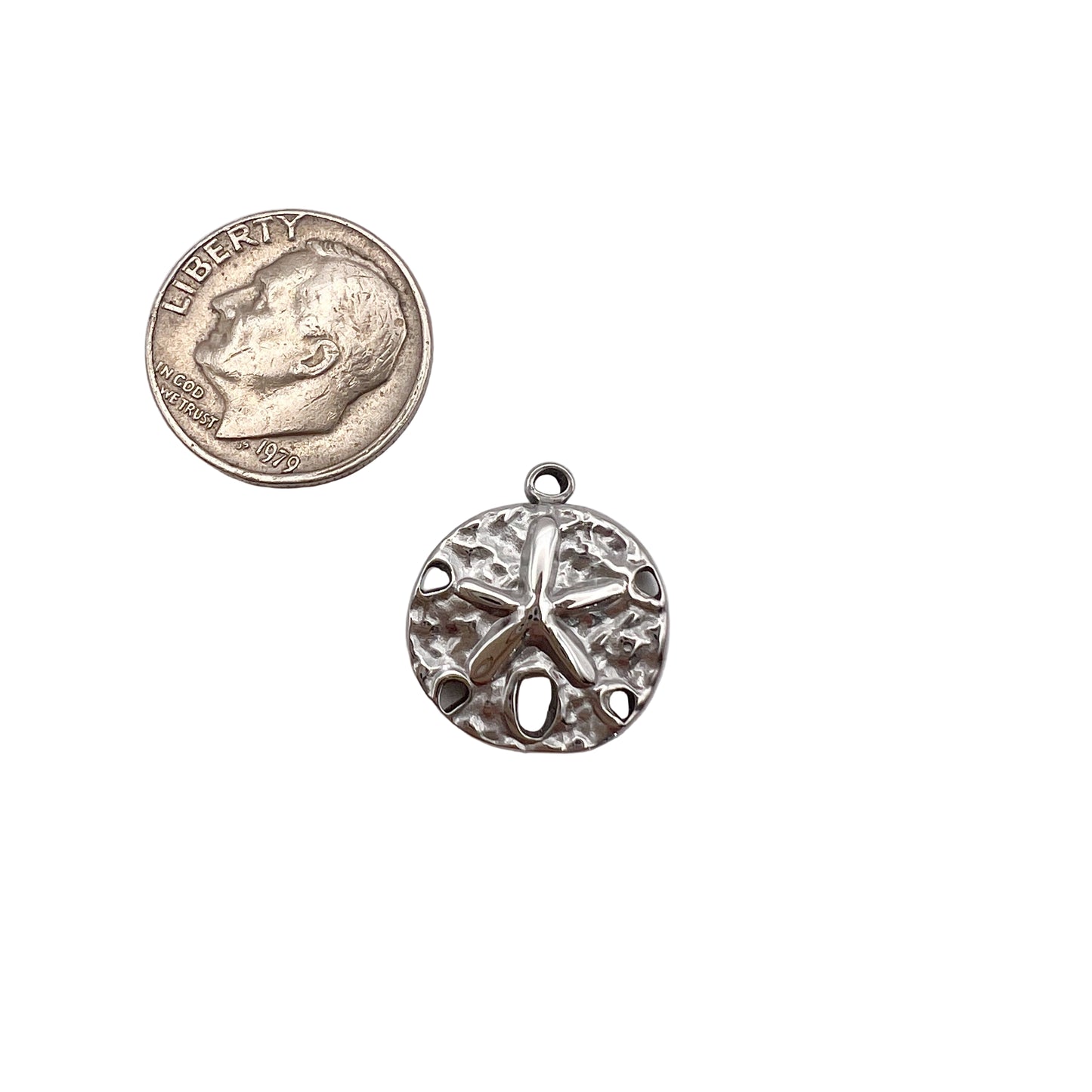 Silver sand dollar pendant next to a quarter on a light gray background