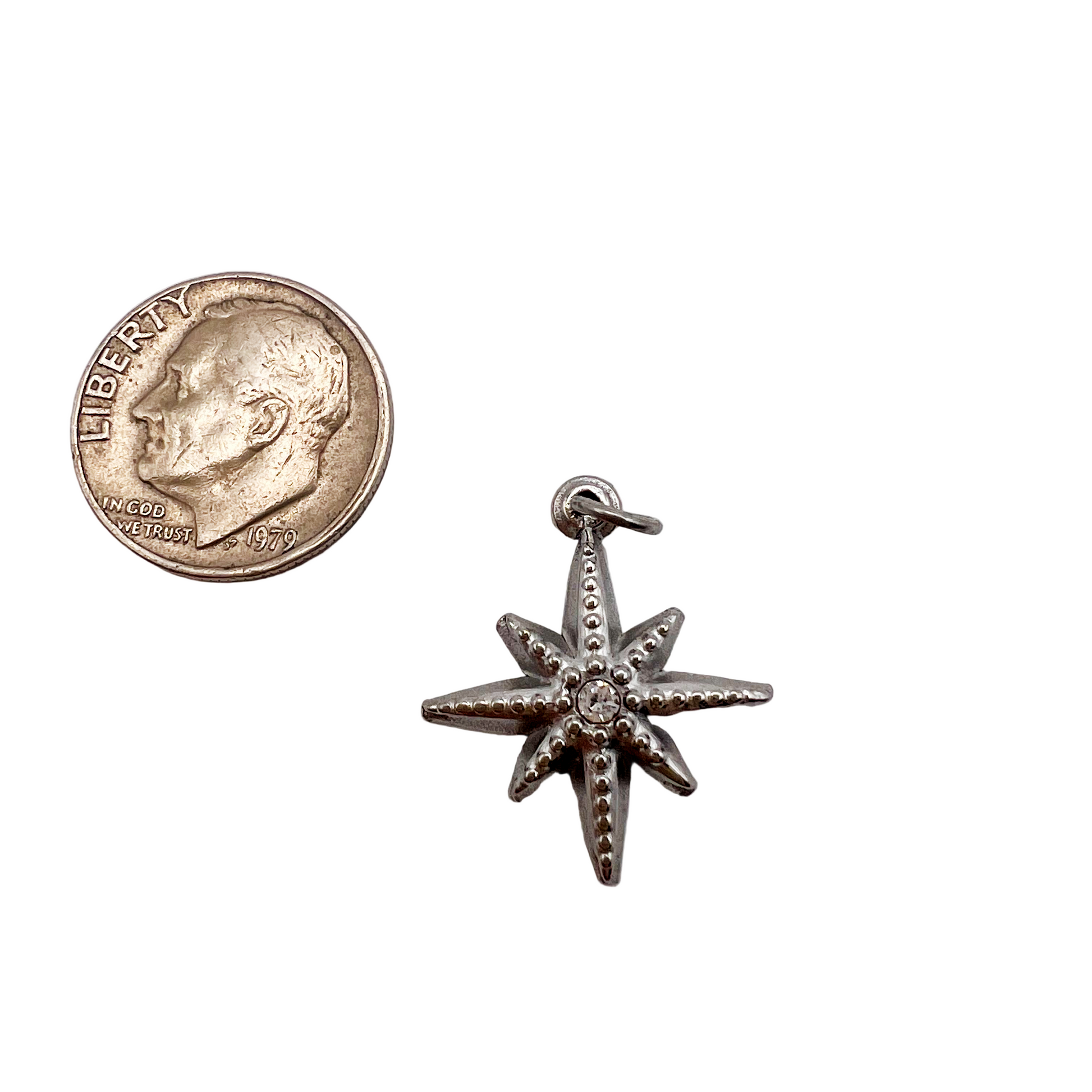 Silver starfish charm next to a U.S. quarter coin on a white background
