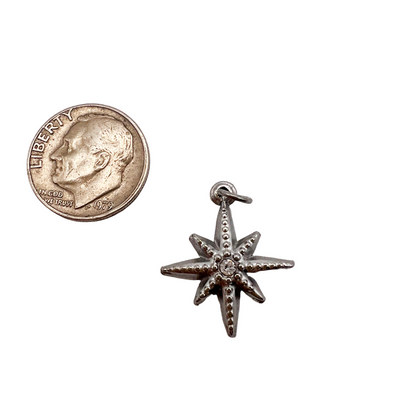 Silver starfish charm next to a U.S. quarter coin on a white background