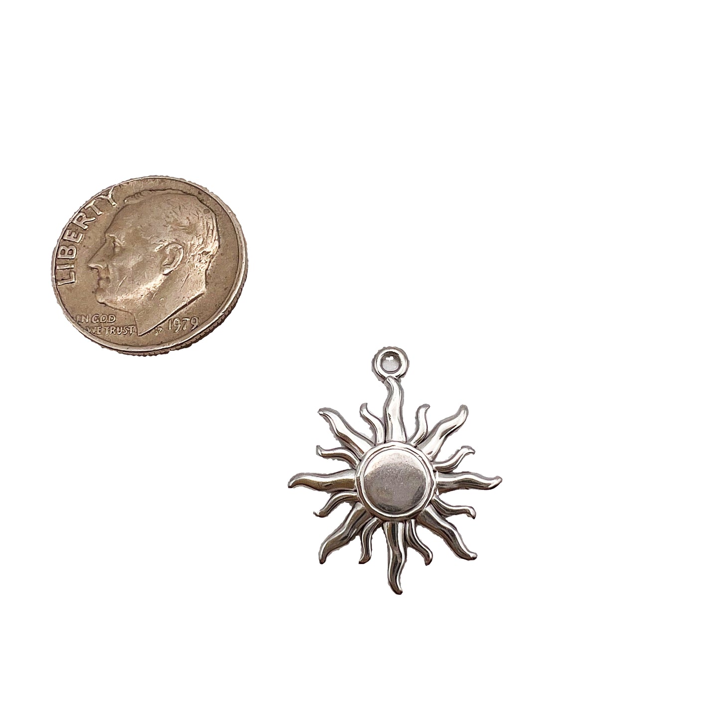 Silver sun-shaped pendant next to a quarter on a white background