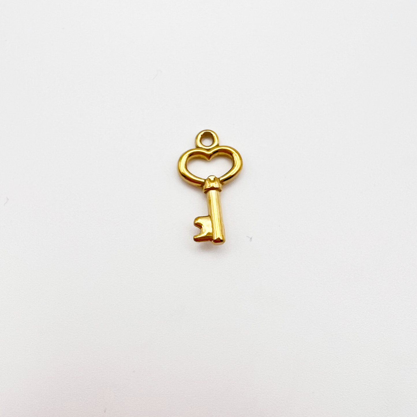 Gold key-shaped charm on a white background