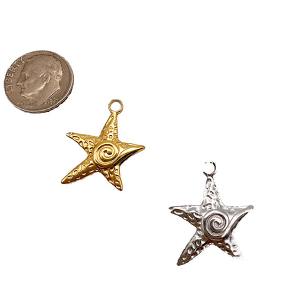 Gold and silver star-shaped pendants on a white background with a quarter for scale.